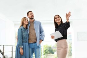 A couple and real estate agent reviewing a home inspection report at a kitchen table.