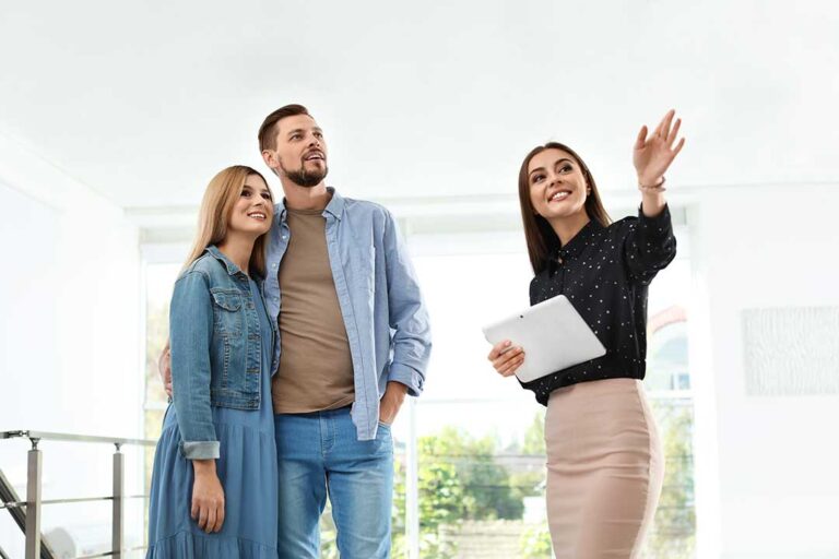 A couple and real estate agent reviewing a home inspection report at a kitchen table.